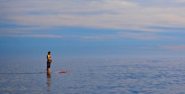 Pratica il paddle surf in alto mare. 